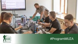 Baner. Pracownicy muzeum siedzą przy długim stole. Przed nimi komputery.