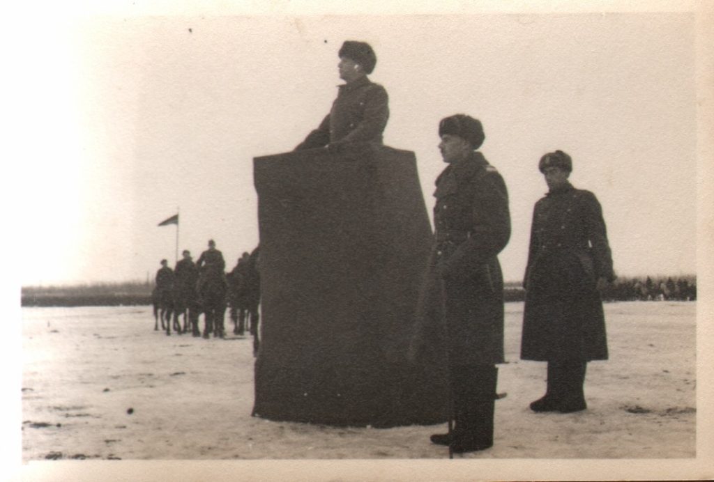 Fotografia czarno-biała. Sikorski stoi na baczność. Ubrany w zimowy płaszcz. Przy boku szabla.