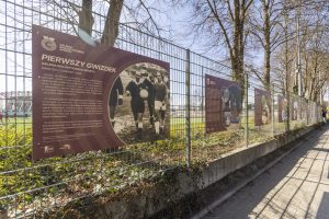 Tablice z wystawą "Pierwszy Gwizdek" zawieszone na płocie przy Chorten Arenie