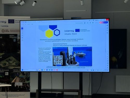 Monitor z prezentacją, widoczne logo programu Interreg.