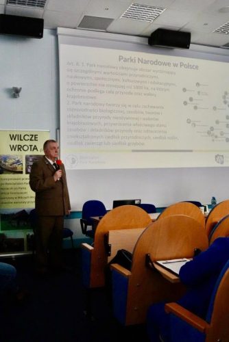 Mężczyzna w mundurze prezentuje treści na dużym ekranie.